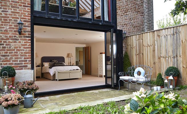 Jet Black aluminium bi-fold doors with five panels opening on a groundfloor bedroom barn conversion
