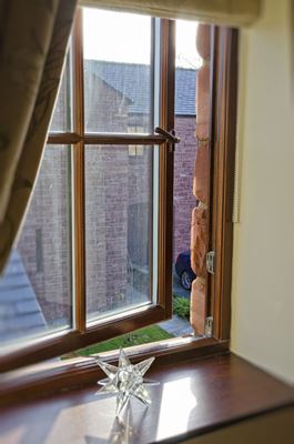 Close up of open wooden casement window with cottage bars finished in Dark Brown with open gold handle from Anglian Home Improvements