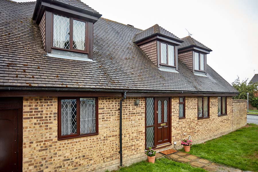 Dark woodgrain wooden casement windows and matching front door