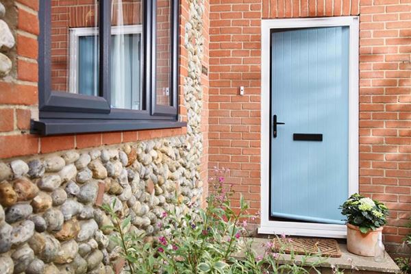 Duck Egg Blue composite door in cottage style with anthracite grey uPVC casement windows on cobbled house