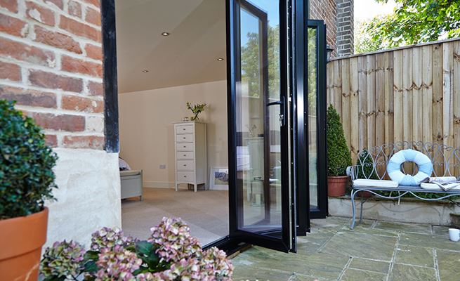Side view of five panel aluminium bifold doors in Jet Black on ground floor bedroom from the Anglian bi-fold doors range