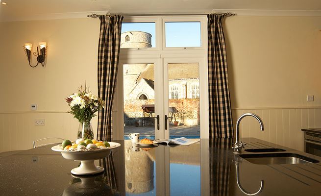White uPVC French doors with uPVC casement windows above in kitchen with large modern kitchen island