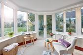 Interior view of solid roof conservatory with White UPVC casement windows and French doors with gold handles from Anglian Home Improvements