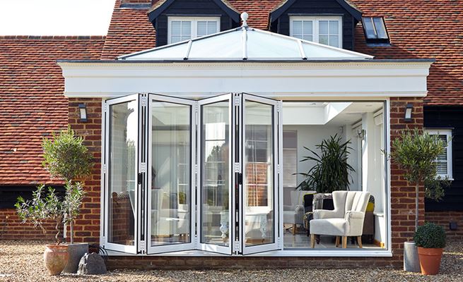 White aluminium bi-fold doors made up of five panels on an orangery from Anglian Home Improvements