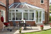 White woodgrain Victorian lean to UPVC conservatory with French doors on modern home from the Anglian conservatory range